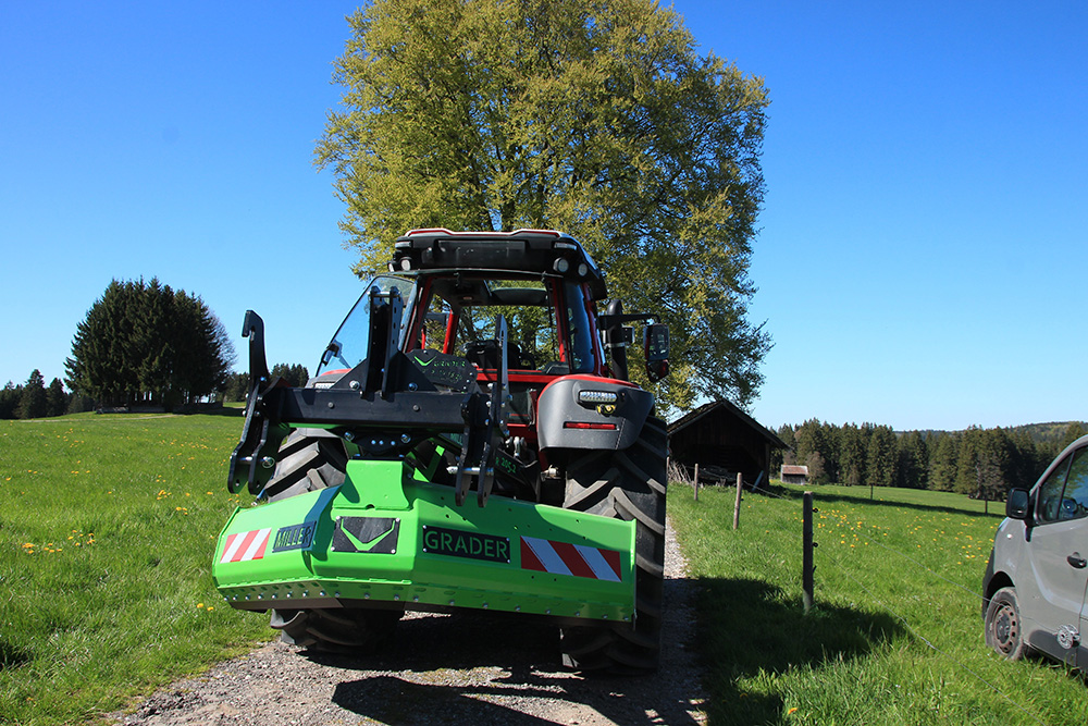 Grader der Firma Miller Grader in gruen angebaut an einem Traktor. Aufnahme von hinten.