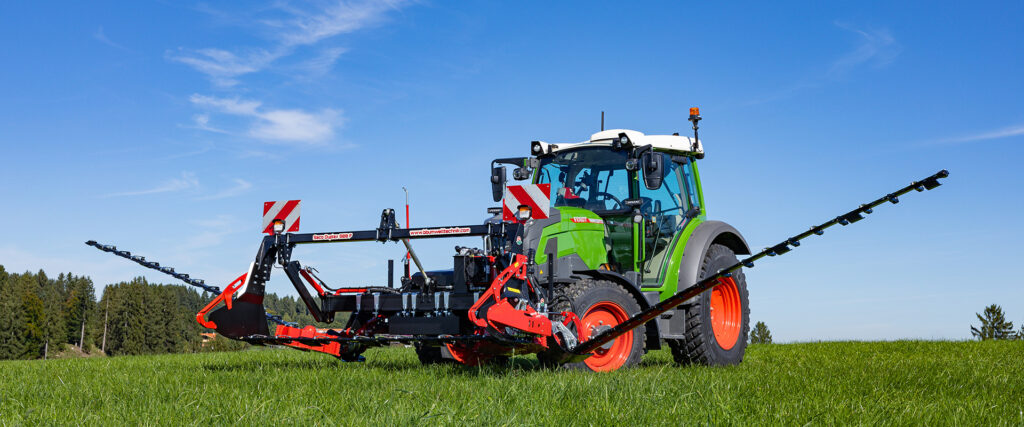 Schmetterlingsmähwerk an einem grünen Traktor auf einer Wiese